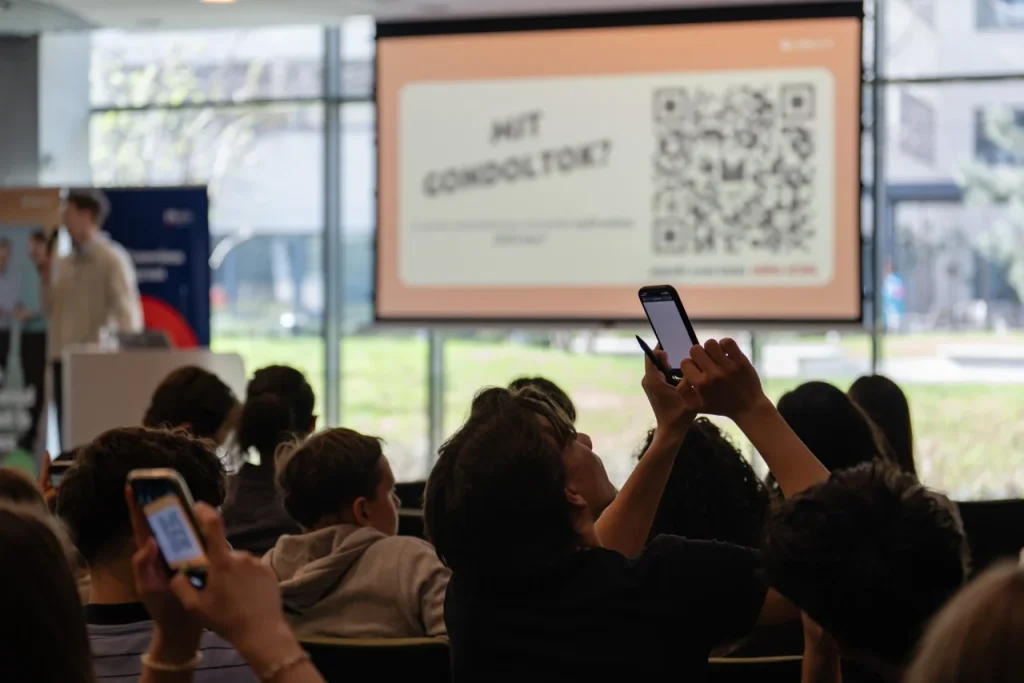 Közönség előadáson QR-kódot fotóz mobiltelefonnal