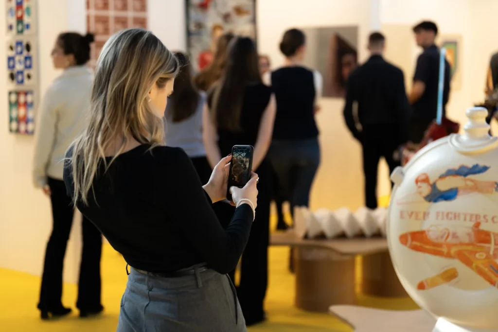 Nő telefonjával fotóz kiállításon