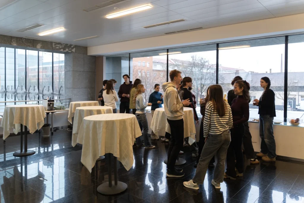 Fiatalok beszélgetnek álló fogadáson állóasztalok mellett