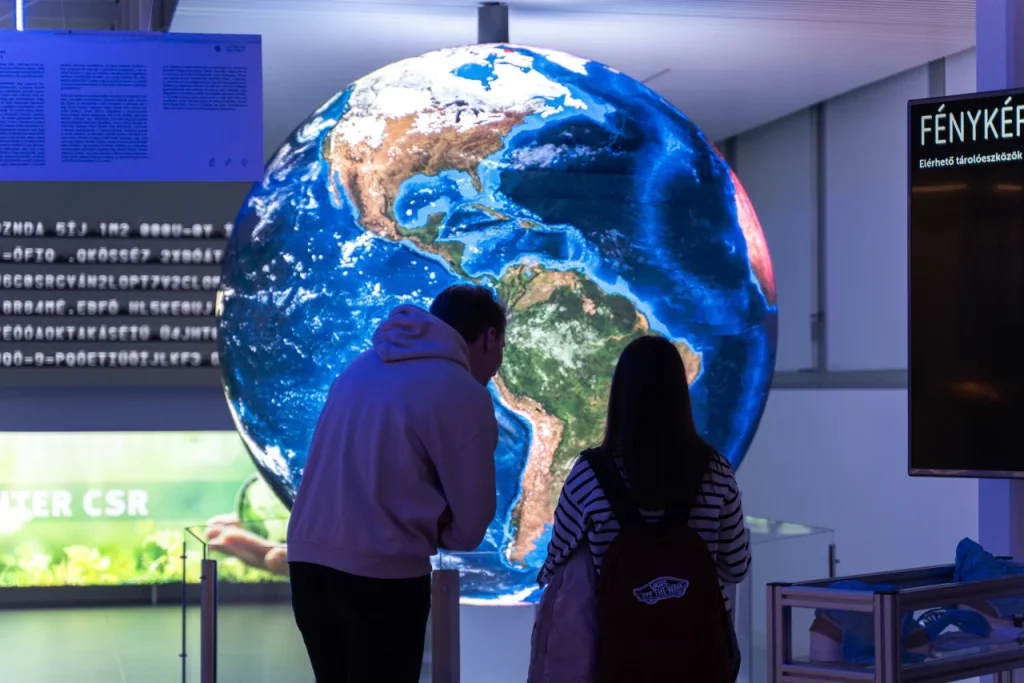 Látogatók világító földgömb installációt néznek
