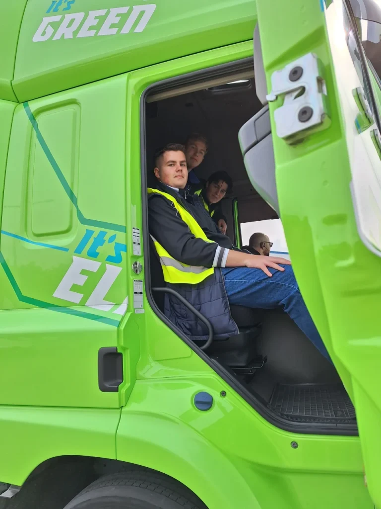 Zöld kamion fülkéjében ülő diákok