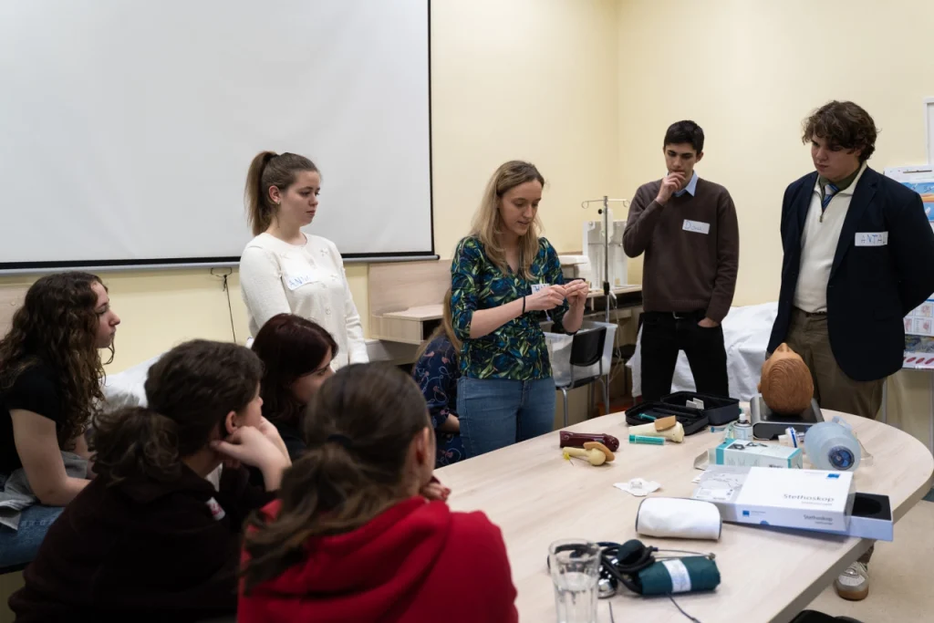 Elsősegély oktatás: csoport figyeli az oktatót és eszközöket